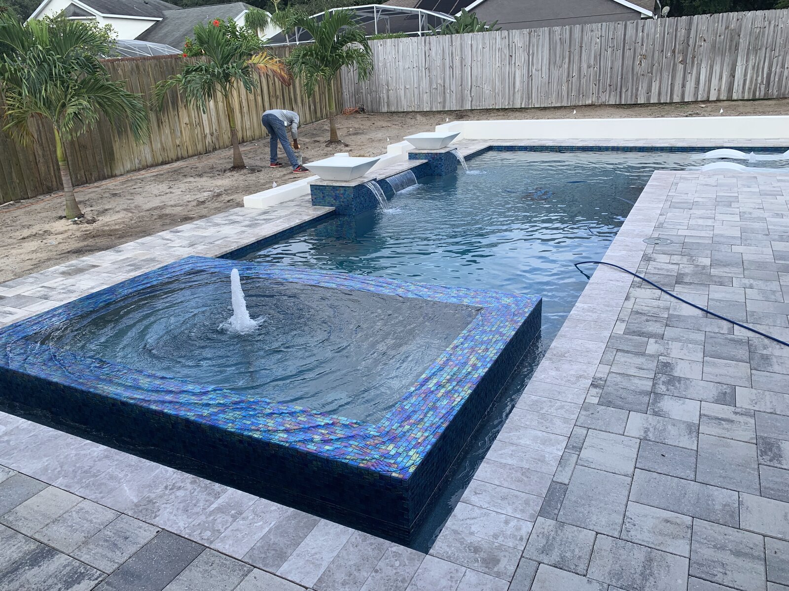 Custom inground pool with sun shelf, iridescent glass tile, bubblers and water feature scuppers built by Mike Jr Kustom Pools in Central Florida