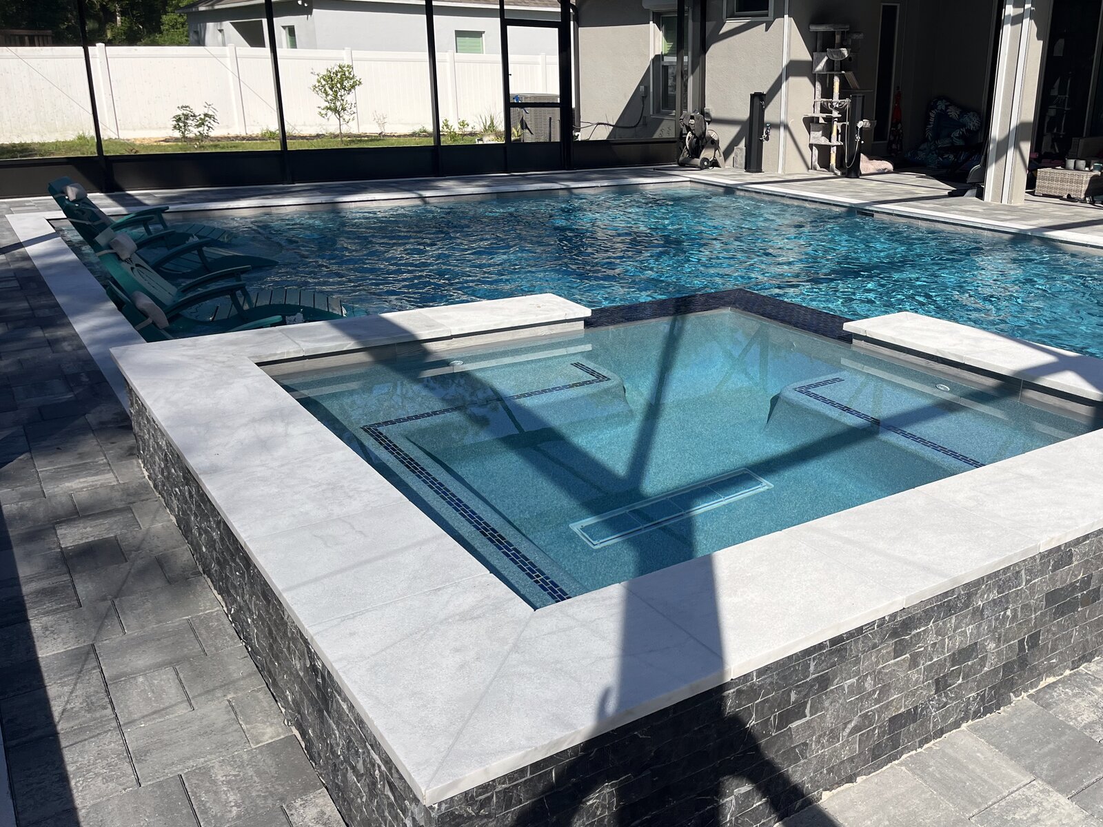 Modern pool with attached spa, spillway, and screen enclosure, Central Florida